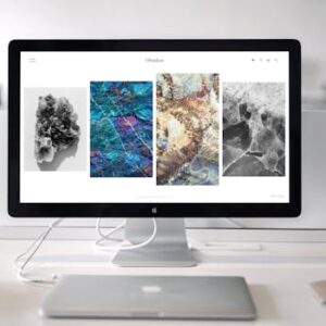 A contemporary office desk setup featuring a sleek computer monitor displaying abstract artwork.
