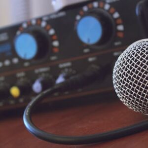 Focused shot of a microphone with audio mixer in background, ideal for media or music themes.