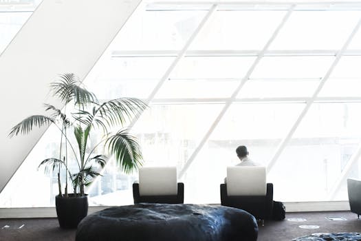 Spacious modern lounge with minimalist decor, featuring large windows and stylish seating.